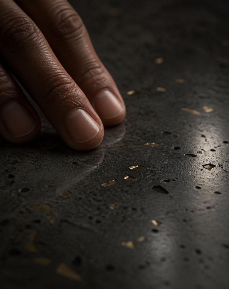 Hand resting on polished concrete with brass flecks